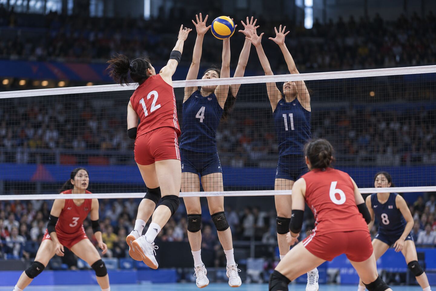 排球比赛中多人协同拦网的竞技画面